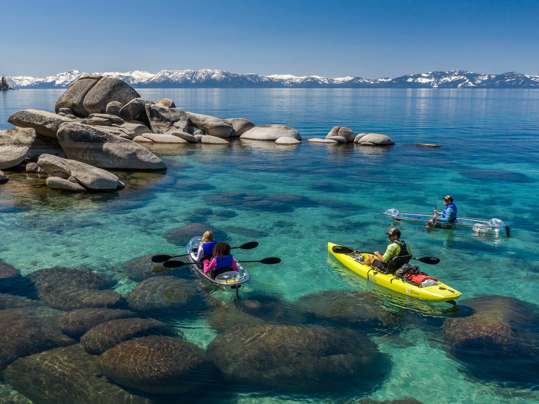 a group of people sitting on a rock next to a body of water