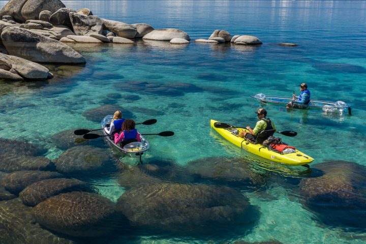 a group of people sitting on a rock next to a body of water