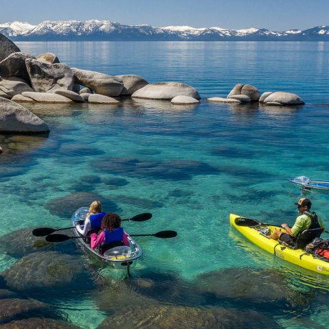 a group of people sitting on a rock next to a body of water