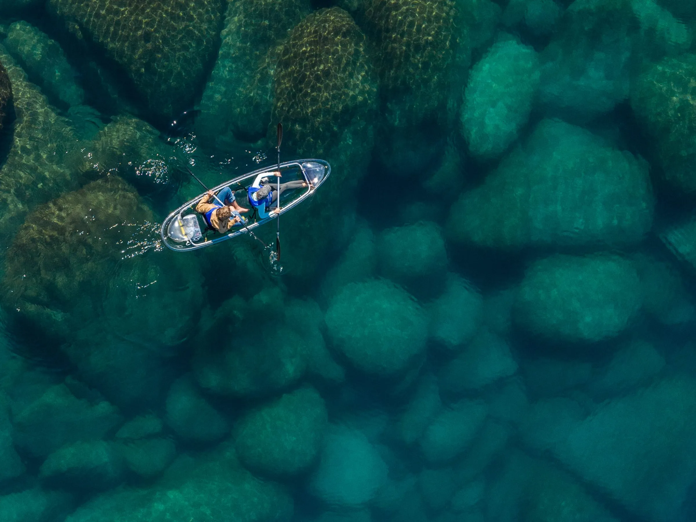 Kayak on clear water with visible underwater rocks.