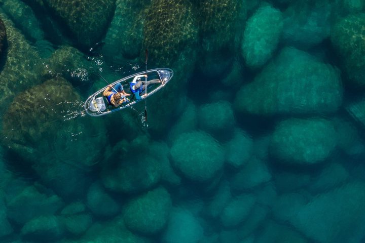 Kayak on clear water with visible underwater rocks.