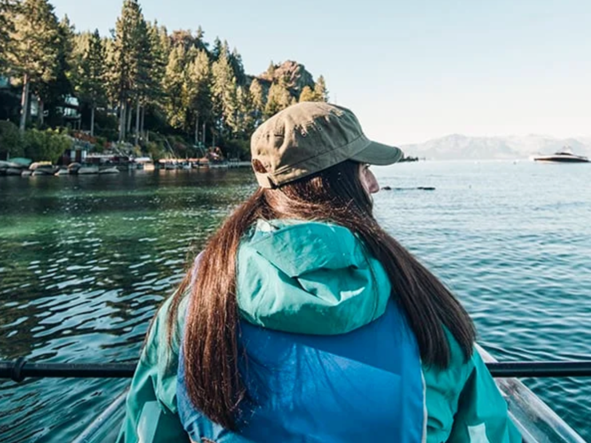 a woman sitting on a bench next to a body of water