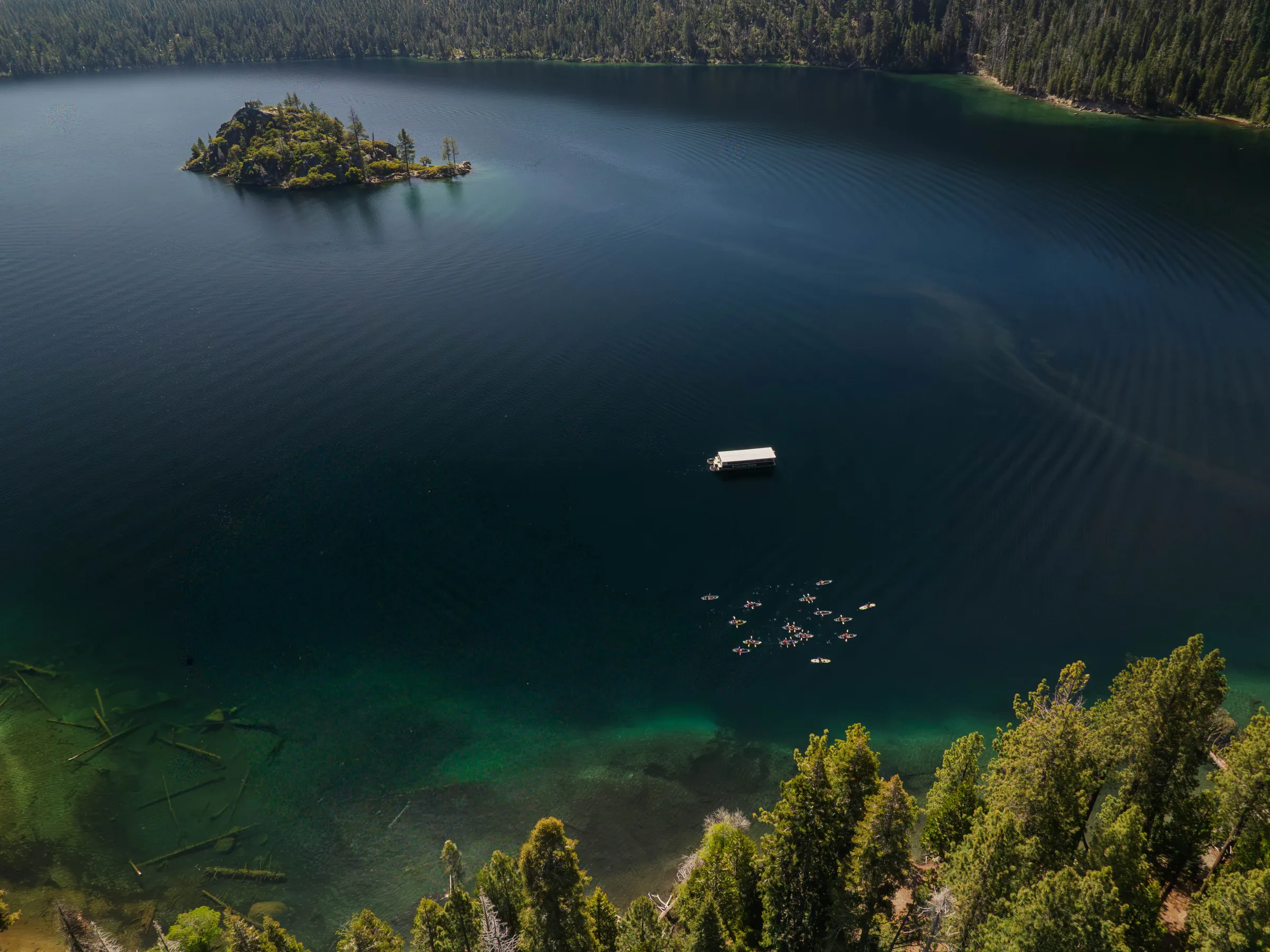 Aerial view of a lake with an island, dock, and surrounding forest.
