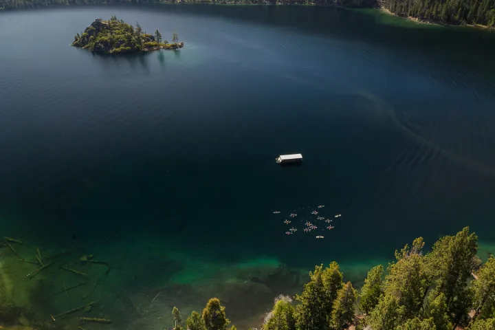 Aerial view of a lake with an island, dock, and surrounding forest.