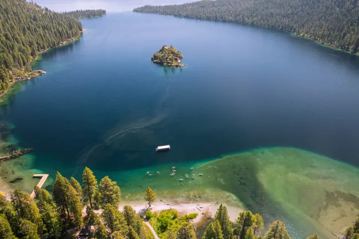 Aerial view of a clear lake with an island and surrounded by forested hills.