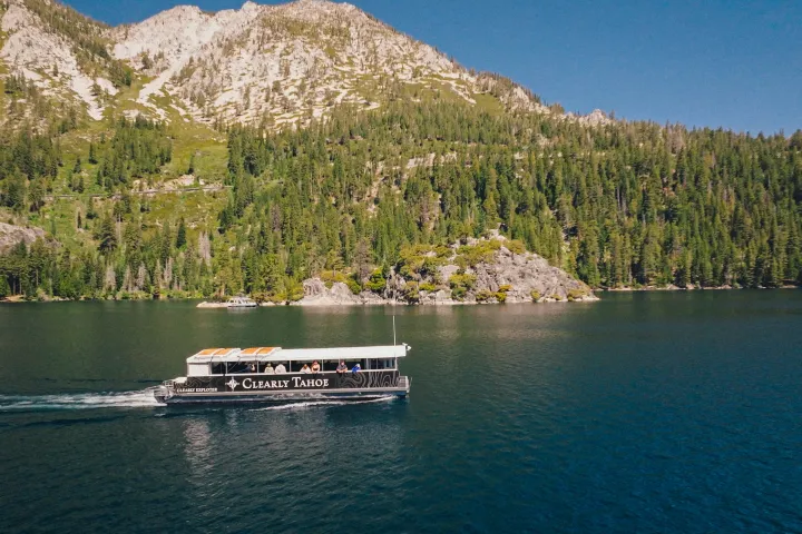 Boat on a lake with forested mountains in the background.