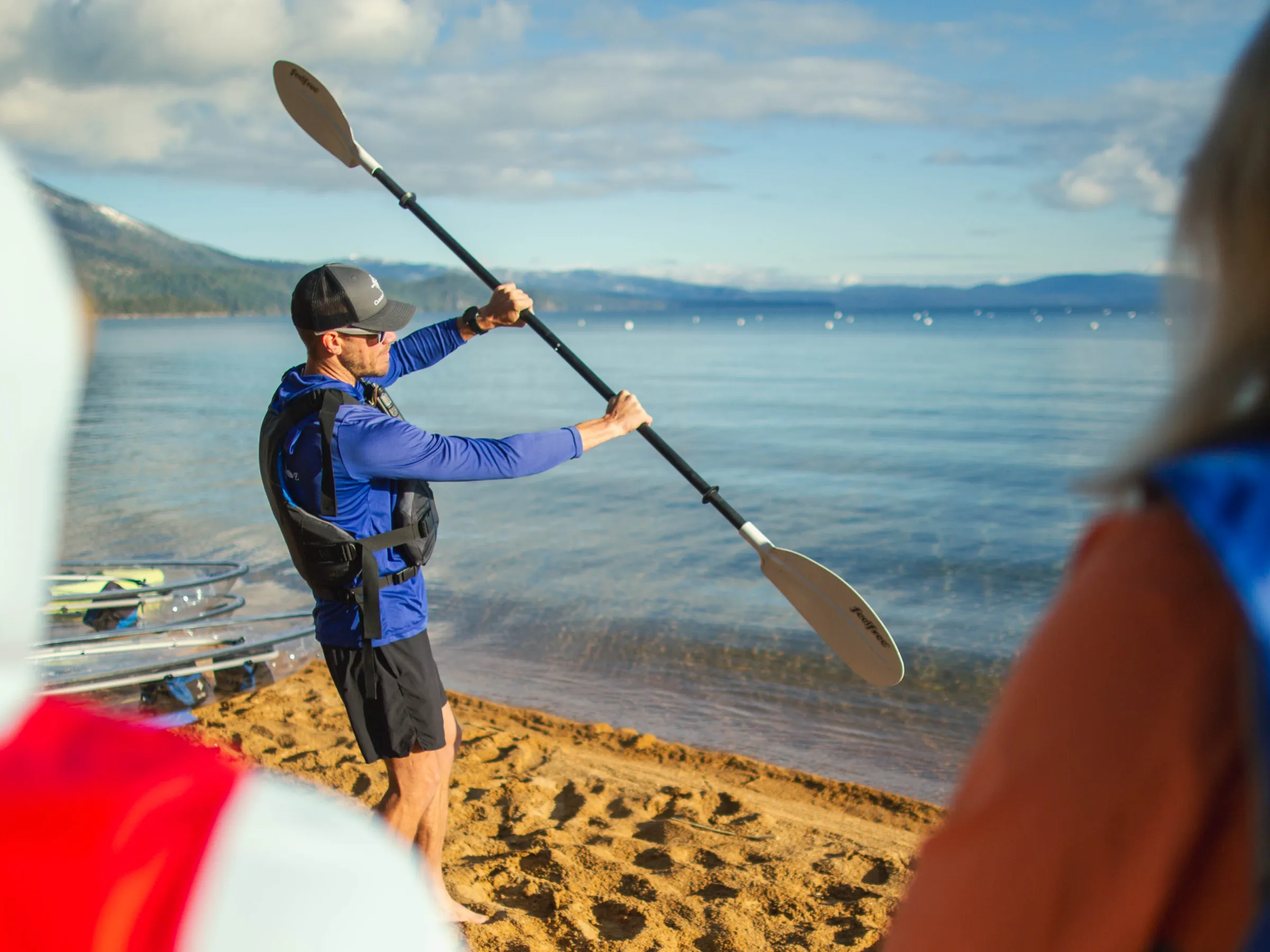 Kayaking instructor on sandy beach demonstrating paddle techniques.