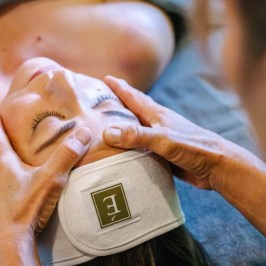 Person receiving a facial massage at a spa, covered with a towel.