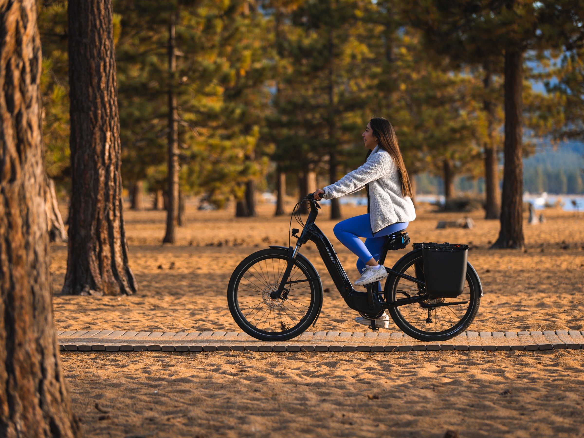 Person rides an electric bike through a forested area in autumn.