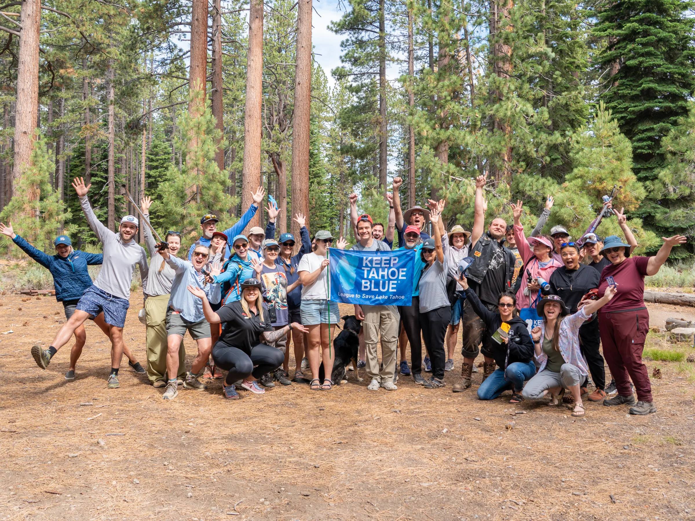Group of people outdoors holding a 'Keep Tahoe Blue' sign, surrounded by trees.
