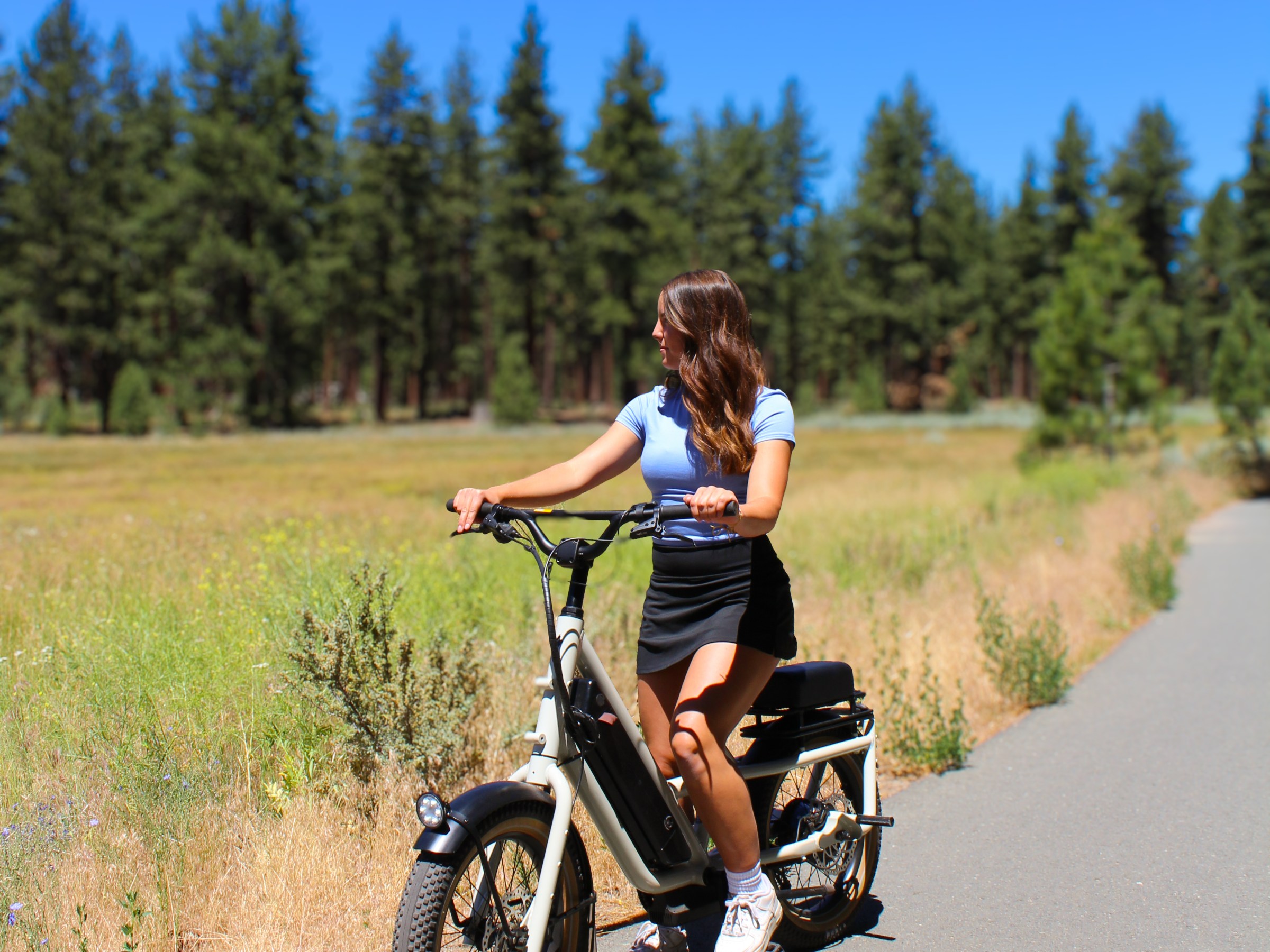 Person on an e-bike on a sunny path with trees.
