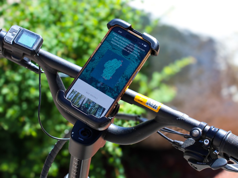 Smartphone with map on handlebar mount of a bicycle, outdoor setting.