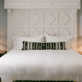 Cozy bedroom with a white bed, patterned headboard, and two bedside lamps.