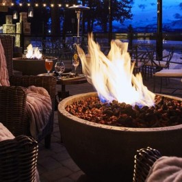 Cozy patio with fire pit and chairs, overlooking mountain view at dusk.