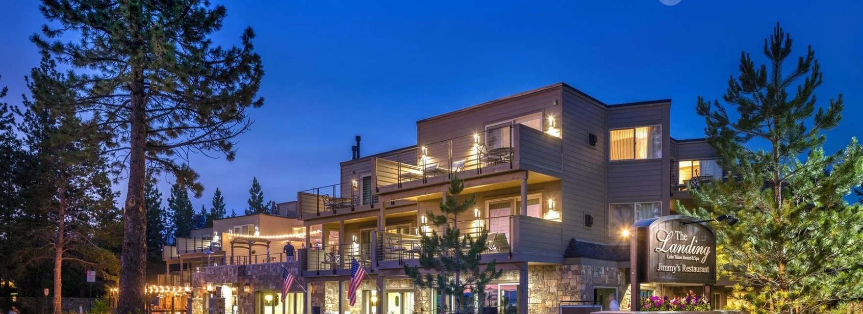 Modern hotel building at twilight with trees and illuminated windows.